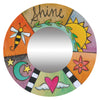 A circular picture frame with a colorful abstract pattern, featuring a sun, stars, a bee, and various other symbols. The word 'Shine' is prominently displayed at the top.