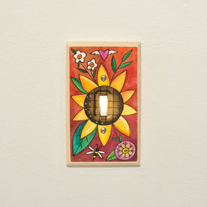 Warm colored floral design with bright sun flower in the middle of a wood light switch plate