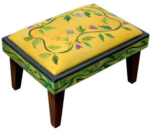 Ottoman – Classic, clean twisting vine ottoman design, both on the leather top and around the wood sides back view
