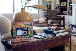 "Grandma's House" Picture Frame – "Life is an Adventure, Partake" frame with home and sunset on the horizon motif displayed on an end table