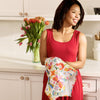 Woman in a red dress holding a floral towel in a kitchen with tulips in the background