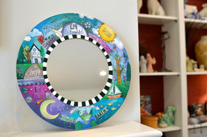 "How to Live Well" decorative circle mirror resting on a fireplace mantle
