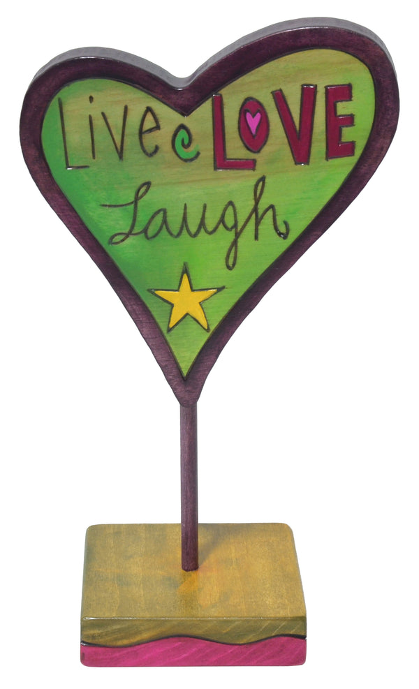 Decorative heart-shaped sculpture with 'Live Love Laugh' text on a stand.