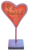 Heart-shaped sculpture with 'Life is Beautiful' text on a stand against a white background