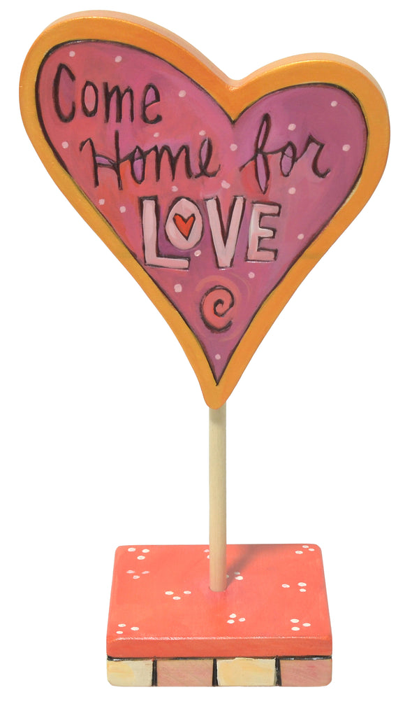 Heart-shaped sculpture with 'Come Home for Love' text on a white background