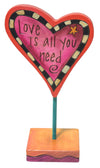 Heart-shaped sign with 'Love is all you need' text on a white background