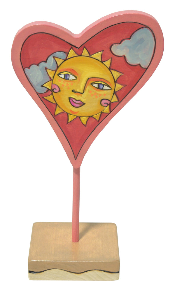 Heart-shaped decoration with a sun design on a white background