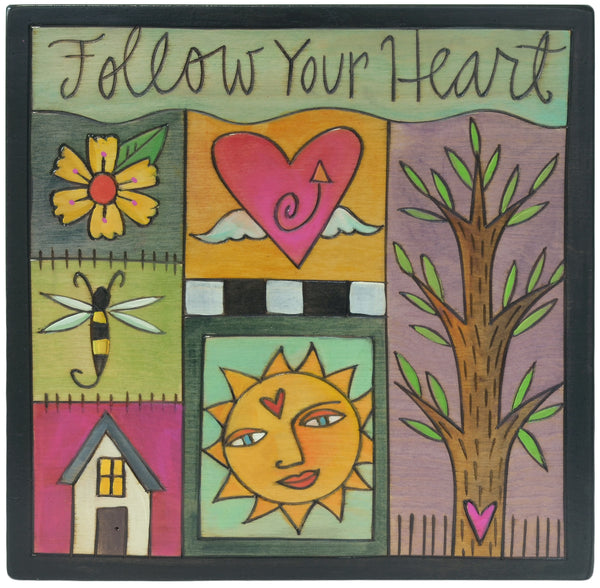 Decorative wall plaque with various symbols including a heart, sun, tree, and house, with 'Follow Your Heart' text at the top.