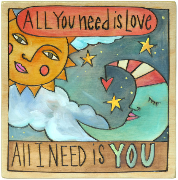 Decorative plaque with sun, moon, and stars design and text 'All You Need is Love, All I Need is You'.
