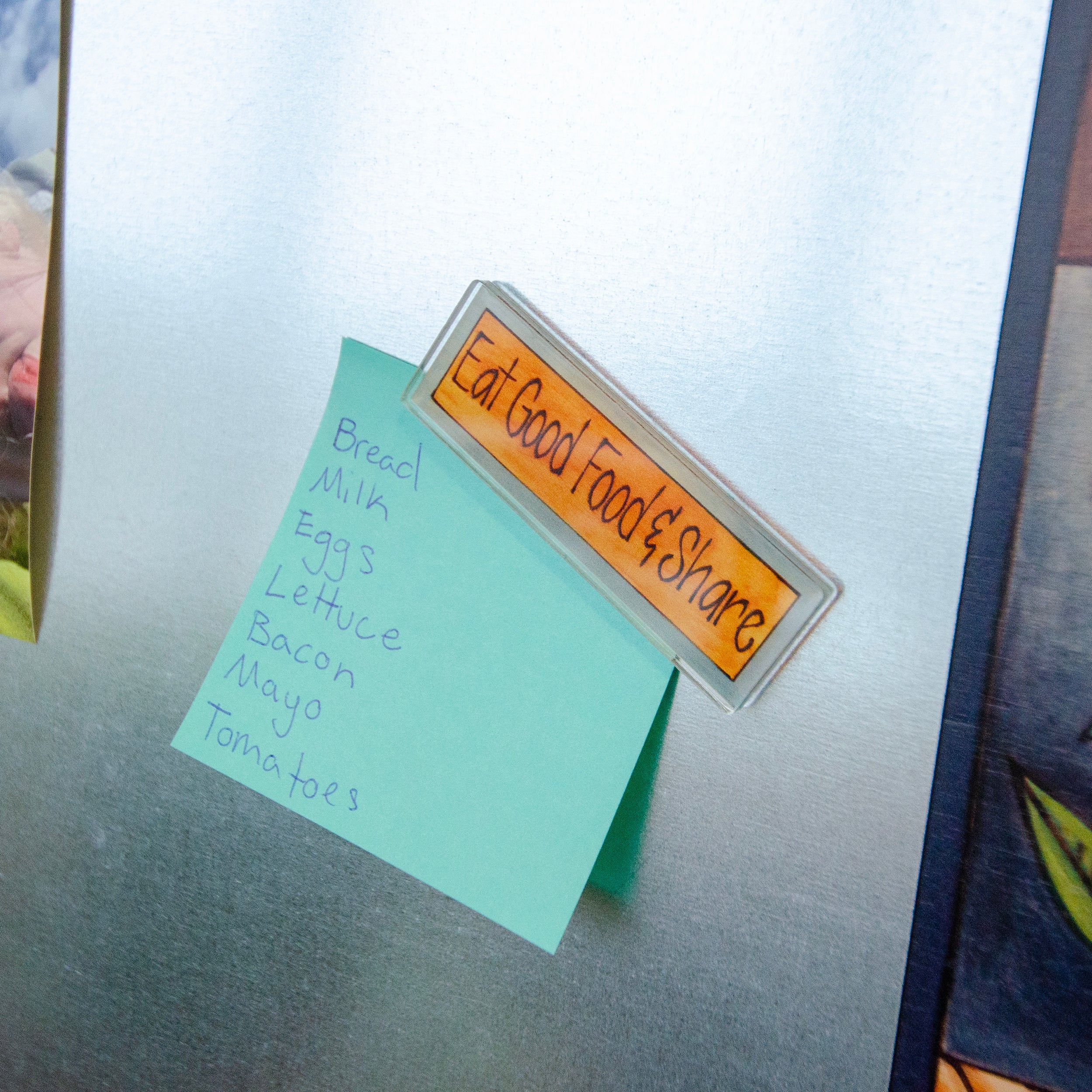 Fridge magnet with a message and a list of groceries attached to a refrigerator.