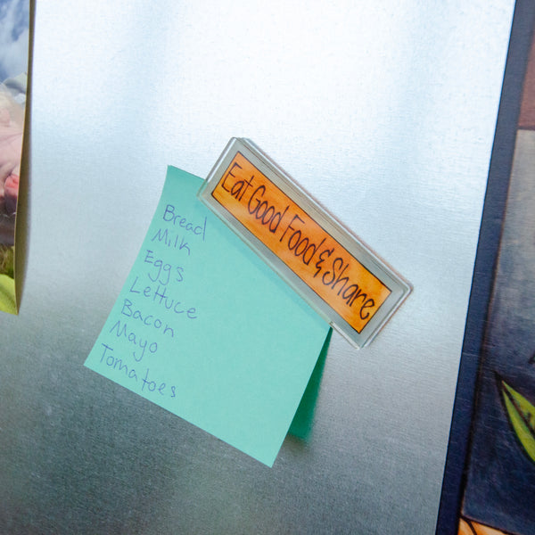Fridge magnet with a message and a list of groceries attached to a refrigerator.
