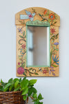Decorative mirror with floral and bird designs and 'Life is Beautiful' text on a white wall.