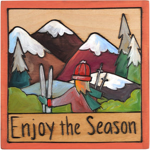 7"x7" Plaque –  "Enjoy the Season" plaque with girl and ski gear in front of the mountains motif