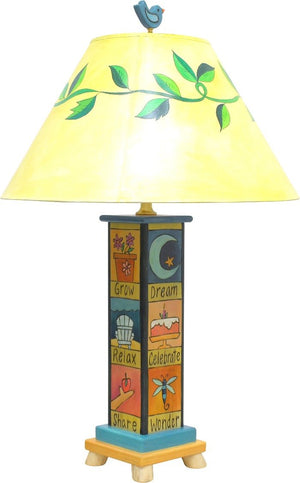 Fun and folky table lamp with vine-wrapped shade, bird finial, and base with cute boxed icons and coordinating phrases, back view