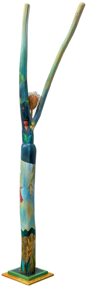 Vibrantly painted with flowers and vines wrapped around the trunk and torso combined with a sky scene. Back view.