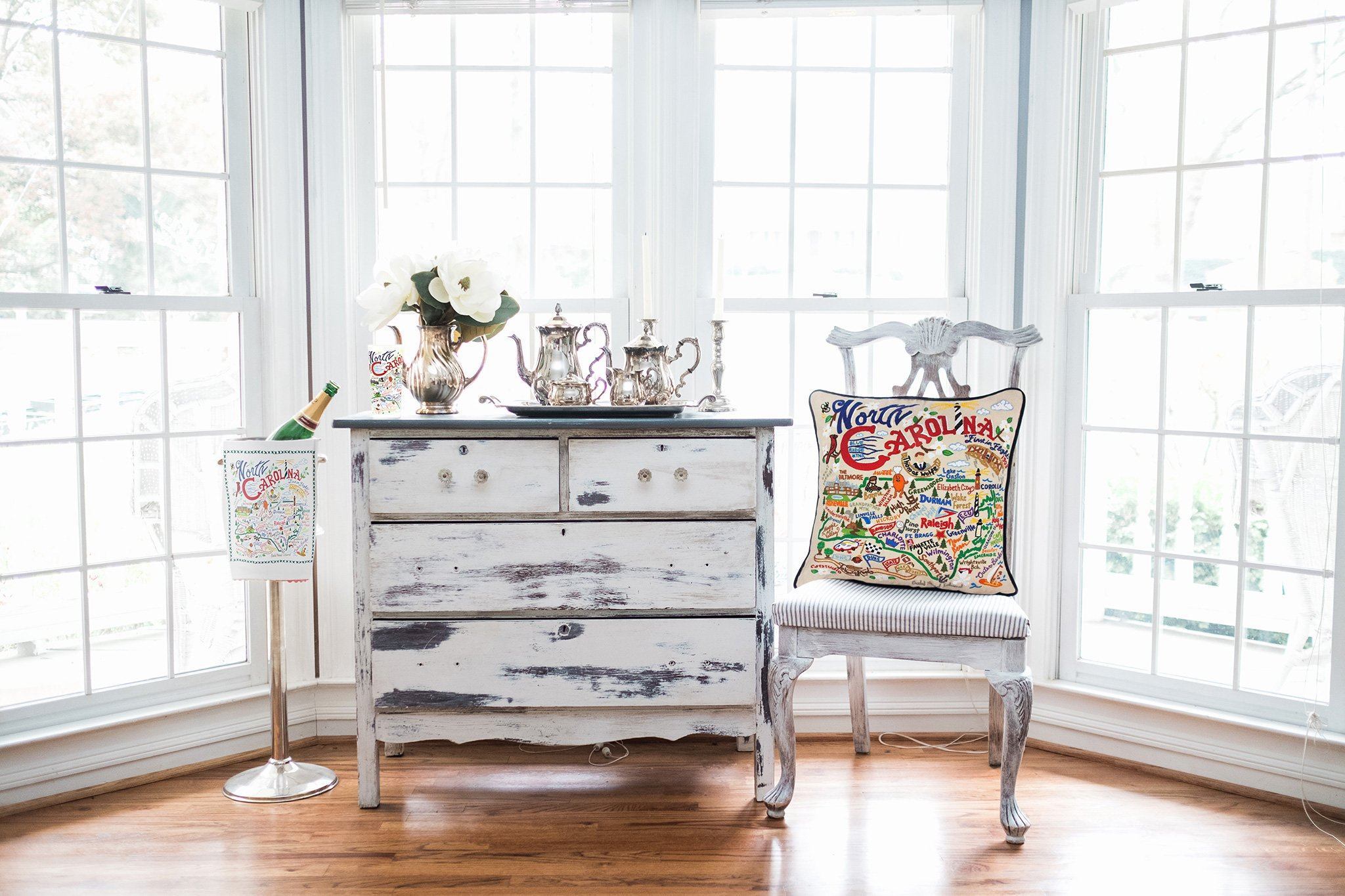 North Carolina Hand-Embroidered Pillow -  What a beautiful state! This original design celebrates the state of North Carolina—from Cape Fear to Asheville to Duck to Kitty Hawk, where man's first flight took place.